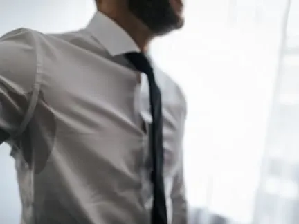Stock photograph of a model: a man in a grey shirt and tie with a sweat patch under his arm
