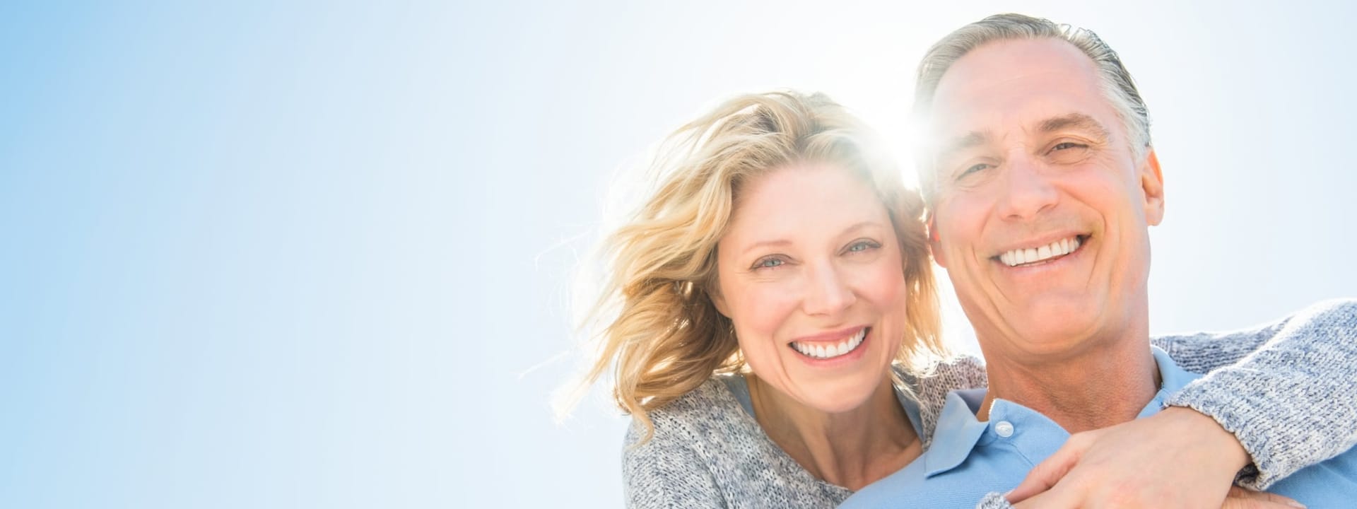Stock photograph of models: a smiling older couple embracing outdoors in bright sunlight