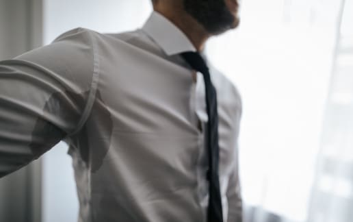 Stock photograph of a model: a man in a grey shirt and tie with a sweat patch under his arm